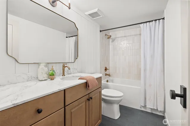 a bathroom with a granite countertop sink toilet a mirror a vanity and shower