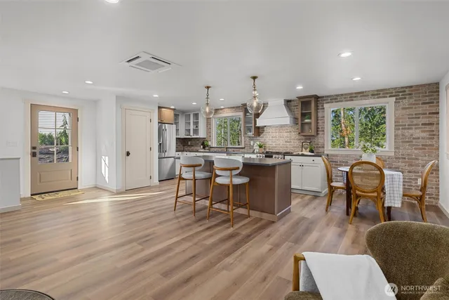 a kitchen with stainless steel appliances granite countertop a stove top oven a sink dishwasher a dining table and chairs with wooden floor