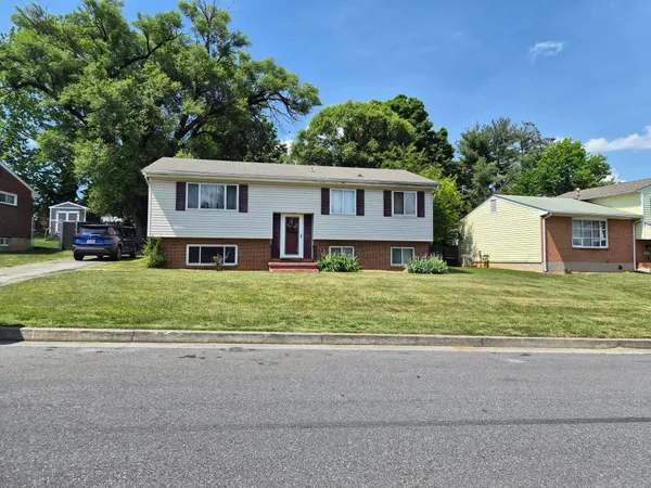 a front view of a house with a yard and trees