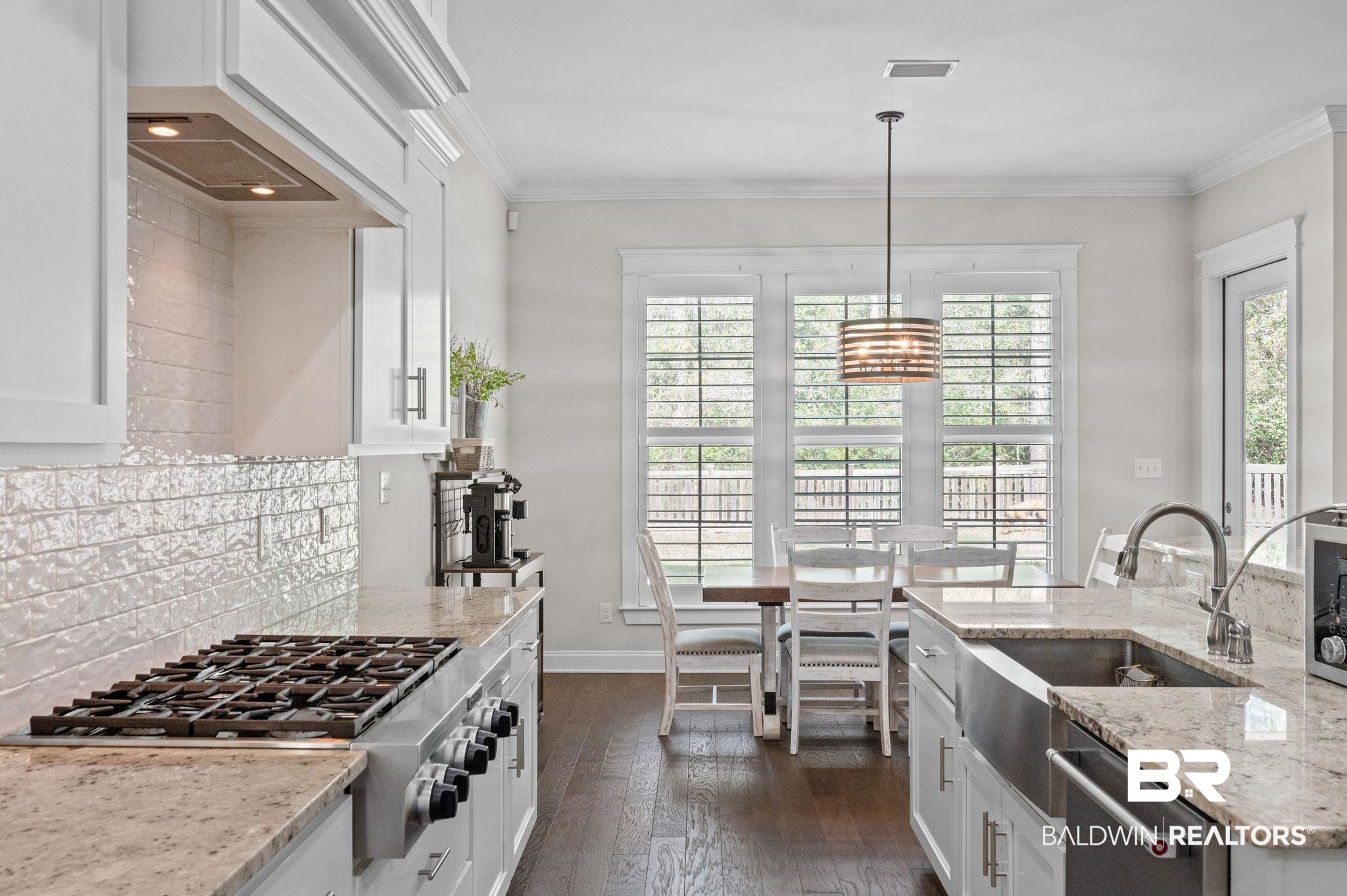 32194 Badger Court Daphne, AL 36527 - Photo 16 of 49 Kitchen featuring white cabinets, light stone counters, stainless steel appliances, dark wood-type flooring, and crown molding