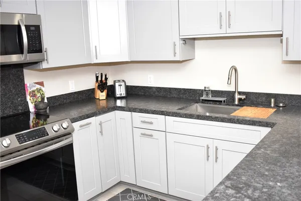 a kitchen with granite countertop white cabinets and a sink
