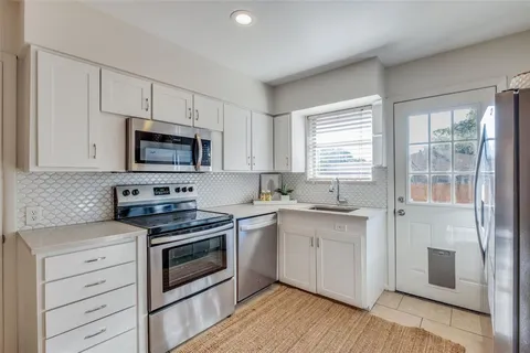 a kitchen with cabinets stainless steel appliances a sink and wooden floor