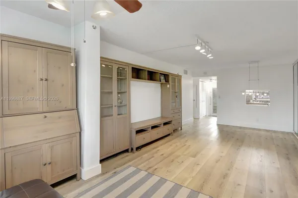 a view of an empty room with wooden floor and cabinet