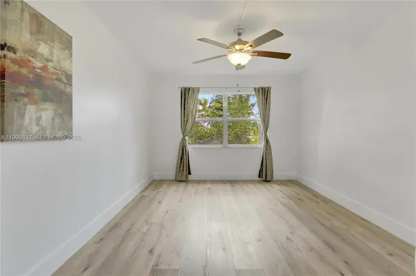 an empty room with wooden floor chandelier fan and windows