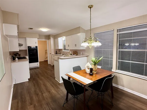 a kitchen with stainless steel appliances kitchen island granite countertop a refrigerator a sink dishwasher and white cabinets with wooden floor