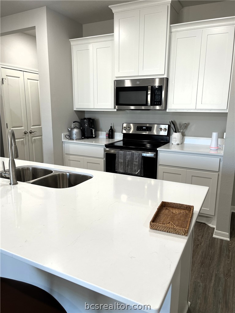 1326 Prairie Drive, Unit 1021 Bryan, TX 77803 - Photo 5 of 17 a kitchen with stainless steel appliances a stove a sink a microwave and cabinets