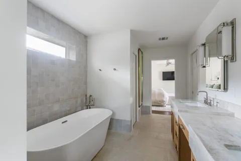 a bathroom with a granite countertop tub sink and mirror