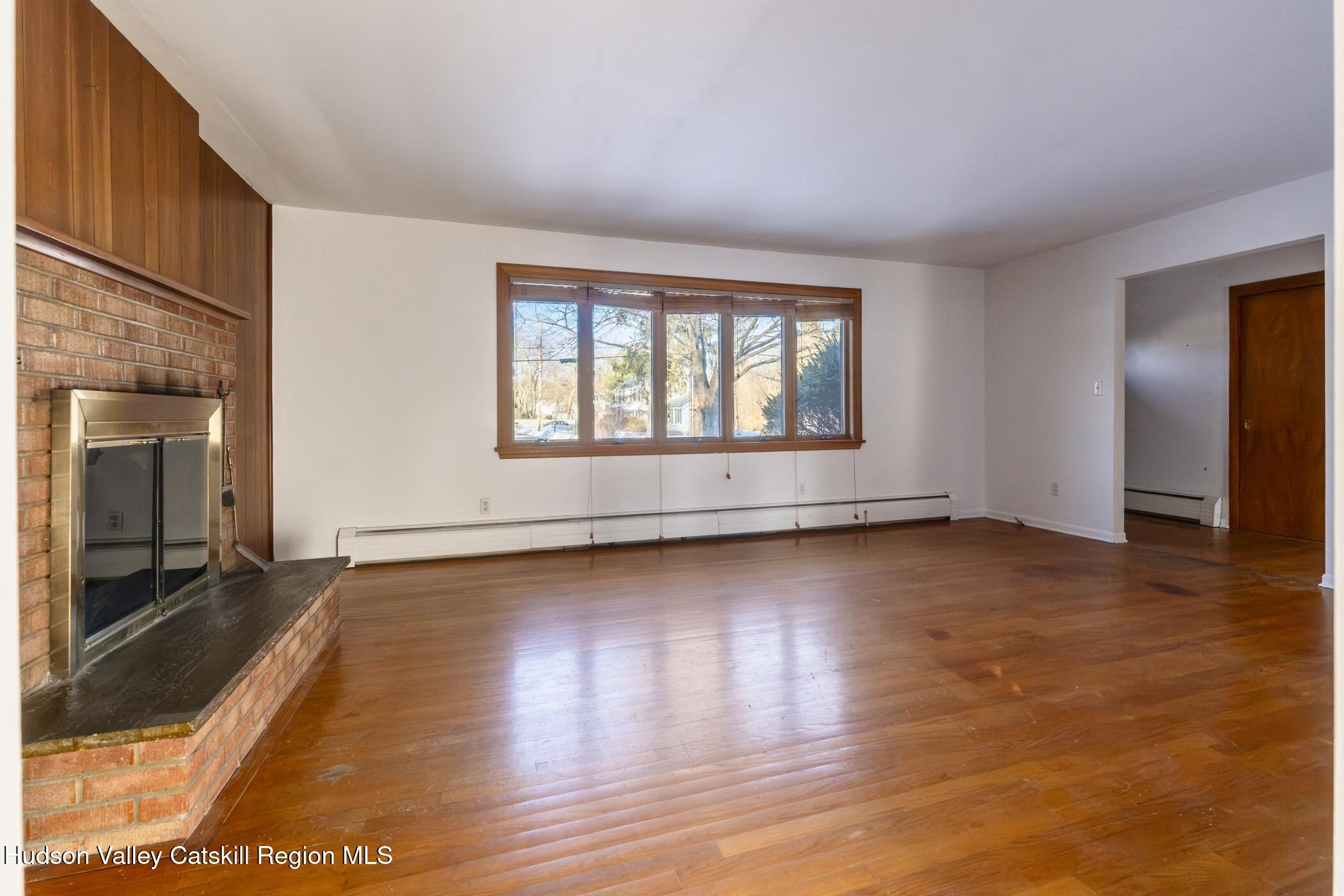609 New Paltz Road Highland, NY 12528 - Photo 7 of 35 an empty room with wooden floor and fireplace