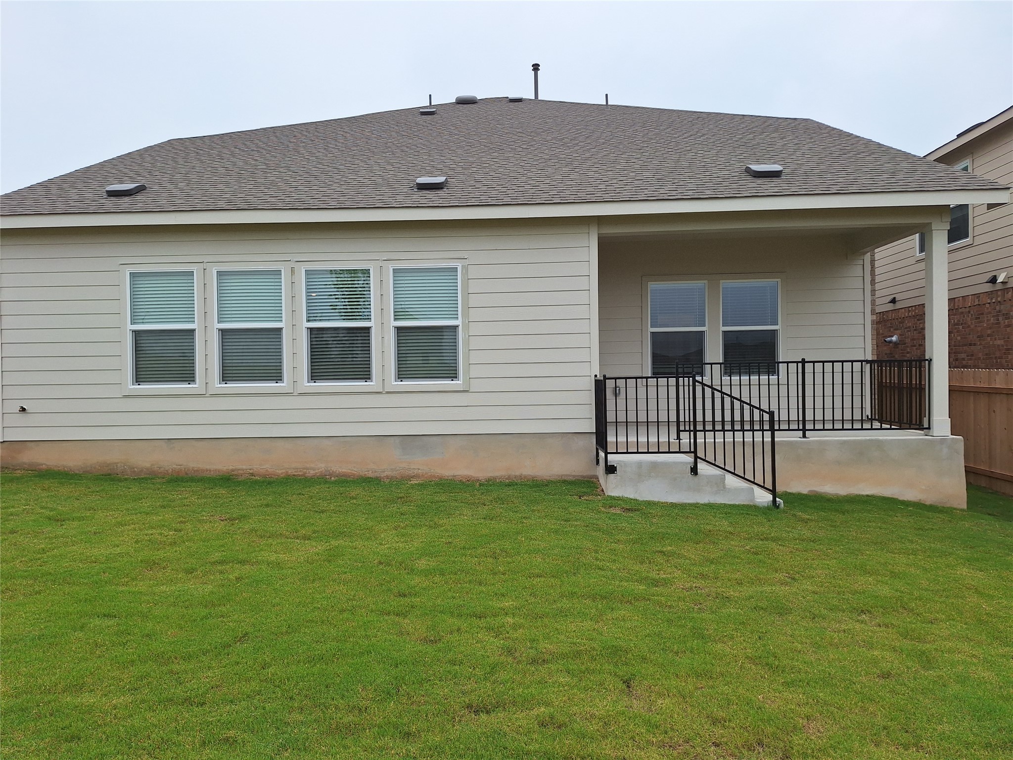18001 Prairie Falcon Way Pflugerville, TX 78660 - Photo 21 of 38 Rear exterior featuring a covered patio with black metal railings, leading to a green lawn