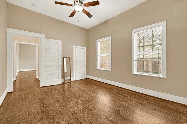 a view of an empty room with wooden floor and a window