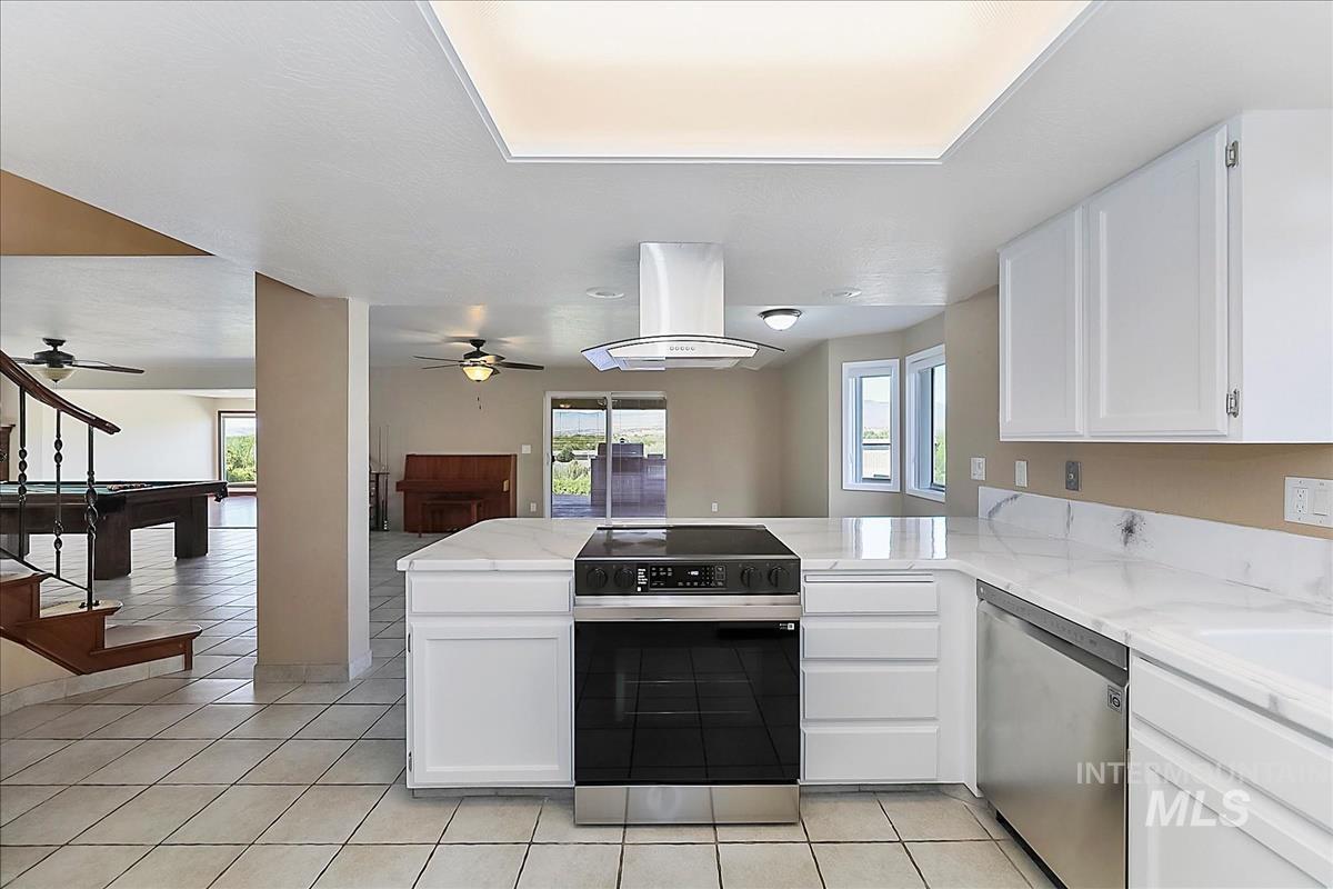 2804 West Sunrise Rim Road Boise, ID 83705 - Photo 10 of 50 Kitchen featuring white cabinetry, light-toned countertops, tile flooring, and stainless steel appliances including a range with a vent hood and a dishwasher
