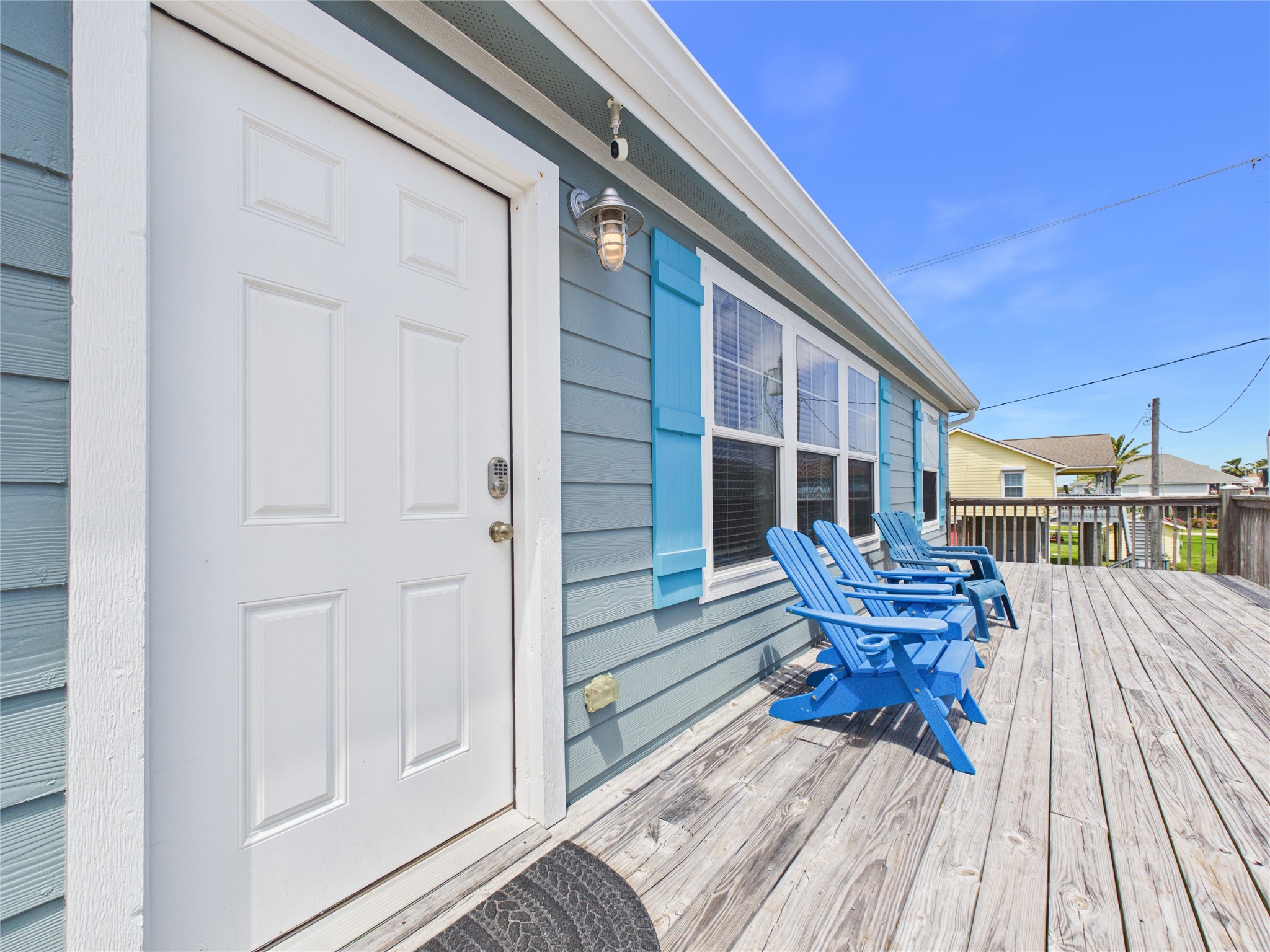 905 Meynig Drive Crystal Beach, TX 77650 - Photo 1 of 50 This inviting home features a spacious wooden deck, perfect for relaxing outdoors. The exterior is painted in a charming light blue with white trim, complemented by large windows that let in plenty of natural light.