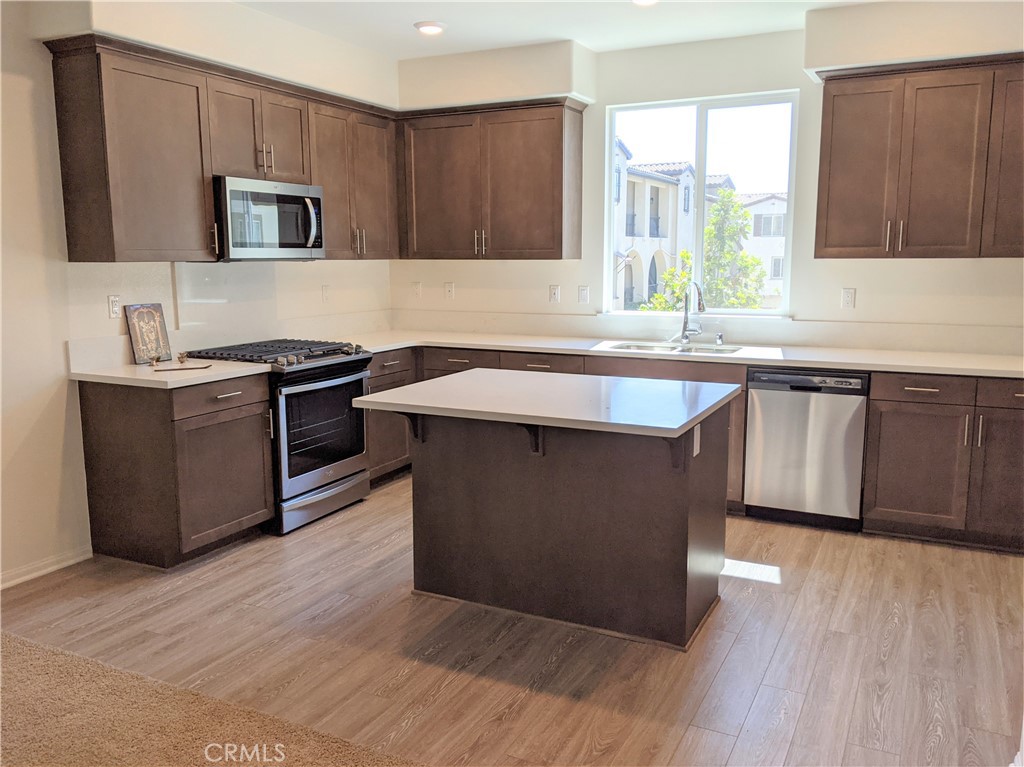 12248 Estrella Drive Rancho Cucamonga, CA 91739 - Photo 2 of 26 a kitchen with granite countertop a stove top oven a sink dishwasher and a microwave oven on the wooden floor