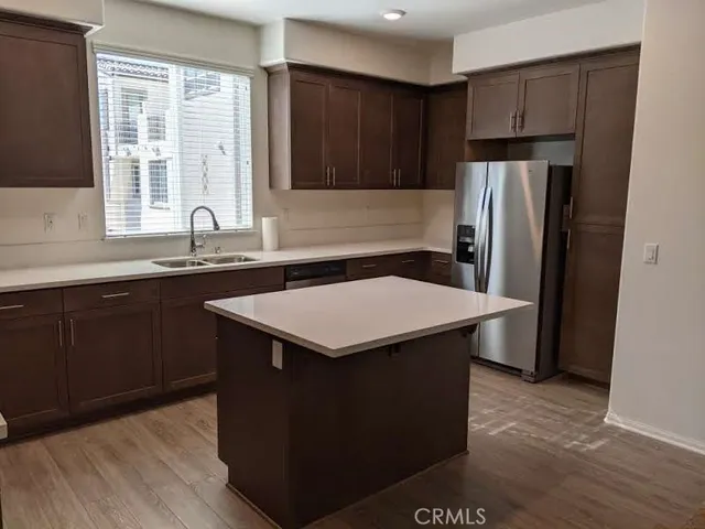 a kitchen with a sink a refrigerator and wooden cabinets