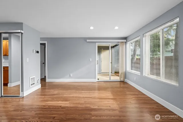 a view of a big room with wooden floor and windows
