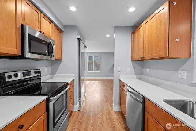 a kitchen with stainless steel appliances granite countertop a refrigerator stove a sink and dishwasher with wooden floor