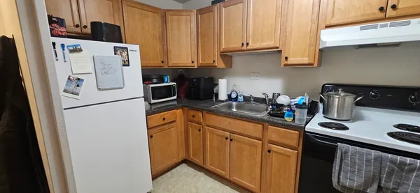 a kitchen with stainless steel appliances granite countertop a refrigerator a sink a stove a counter space and cabinets