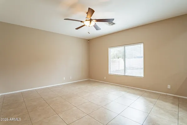 an empty room with chandelier fan and windows