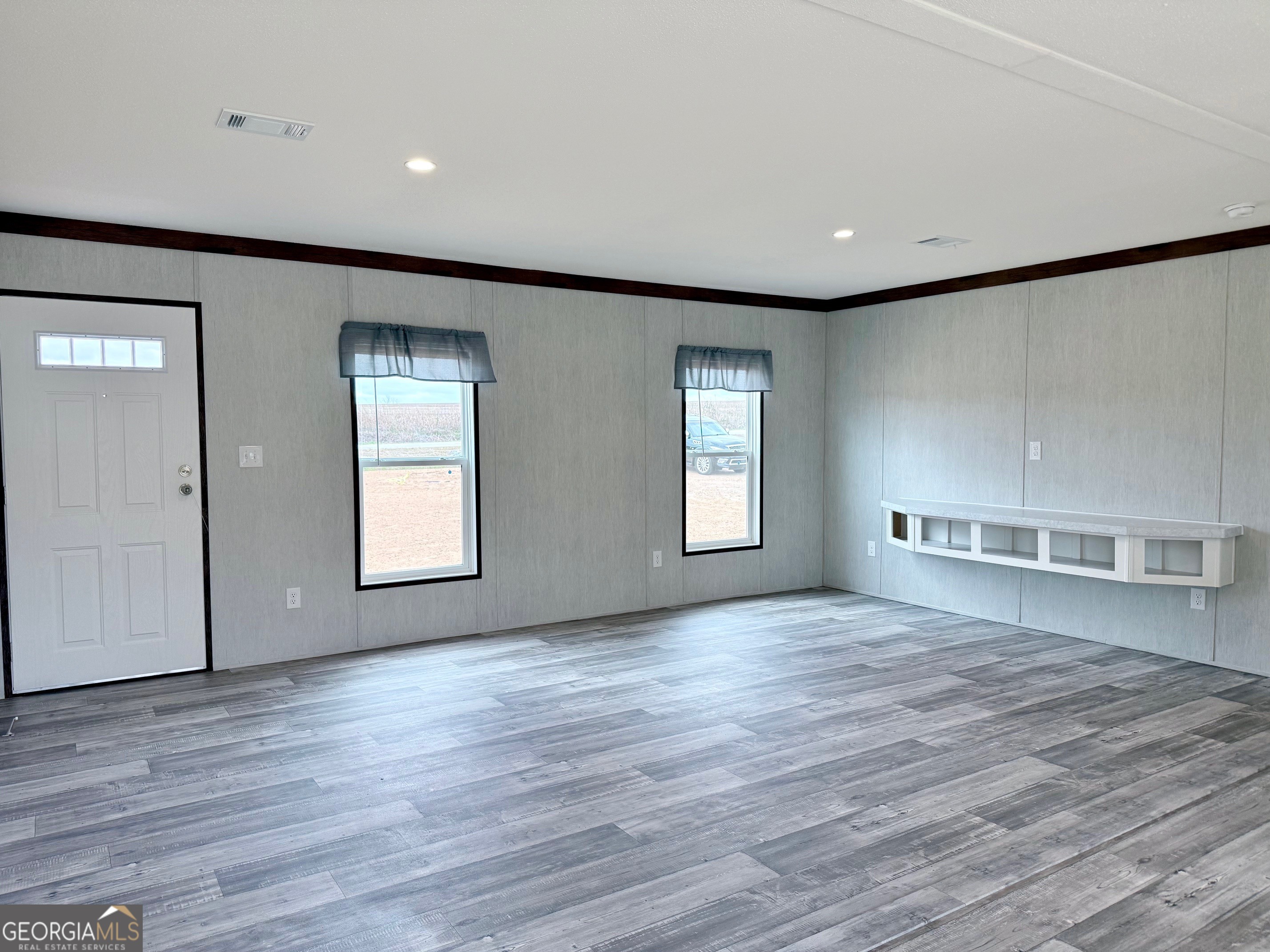 683 Evergreen Church Road Cobbtown, GA 30420 - Photo 2 of 32 an empty room with wooden floor and windows