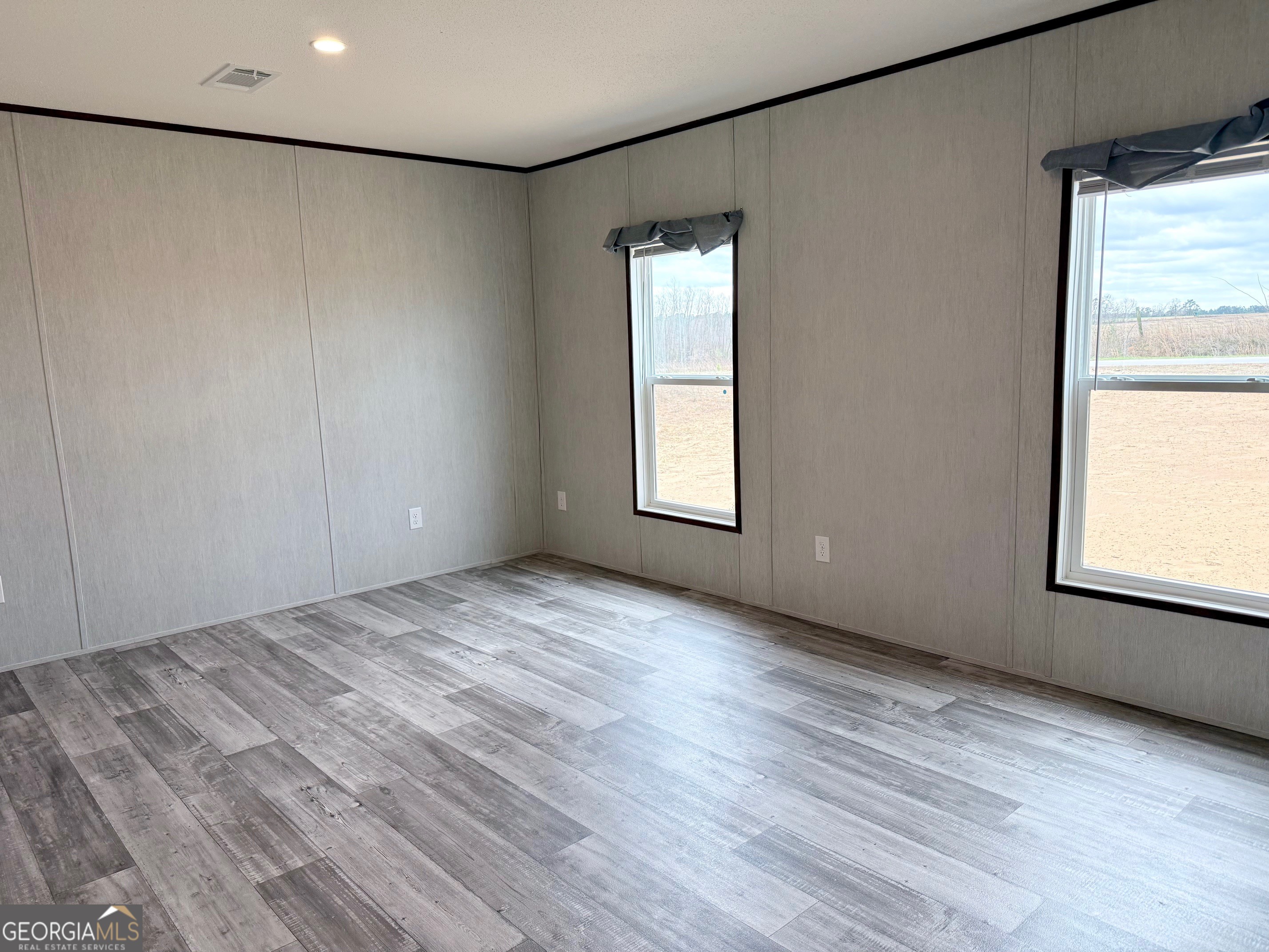 683 Evergreen Church Road Cobbtown, GA 30420 - Photo 10 of 32 an empty room with wooden floor and windows