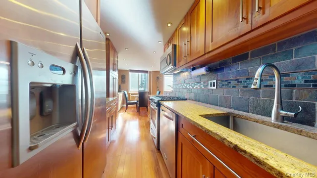 a kitchen with stainless steel appliances granite countertop a sink a stove and a refrigerator