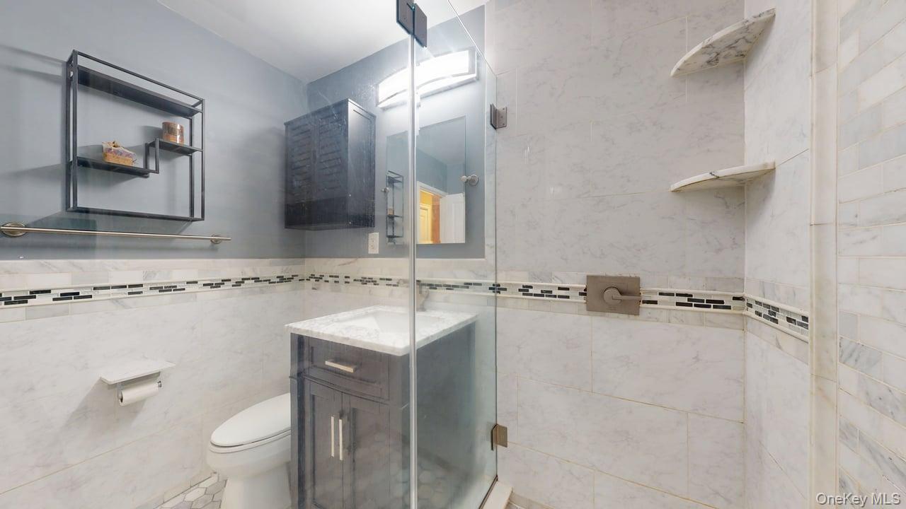 118-17 Union Turnpike, Unit 5H Queens, NY 11375 - Photo 34 of 48 a bathroom with a granite countertop sink mirror toilet and vanity