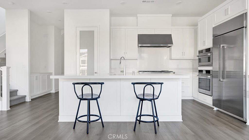 401 Junco Irvine, CA 92618 - Photo 17 of 40 a kitchen with stainless steel appliances kitchen island a table chairs refrigerator and sink