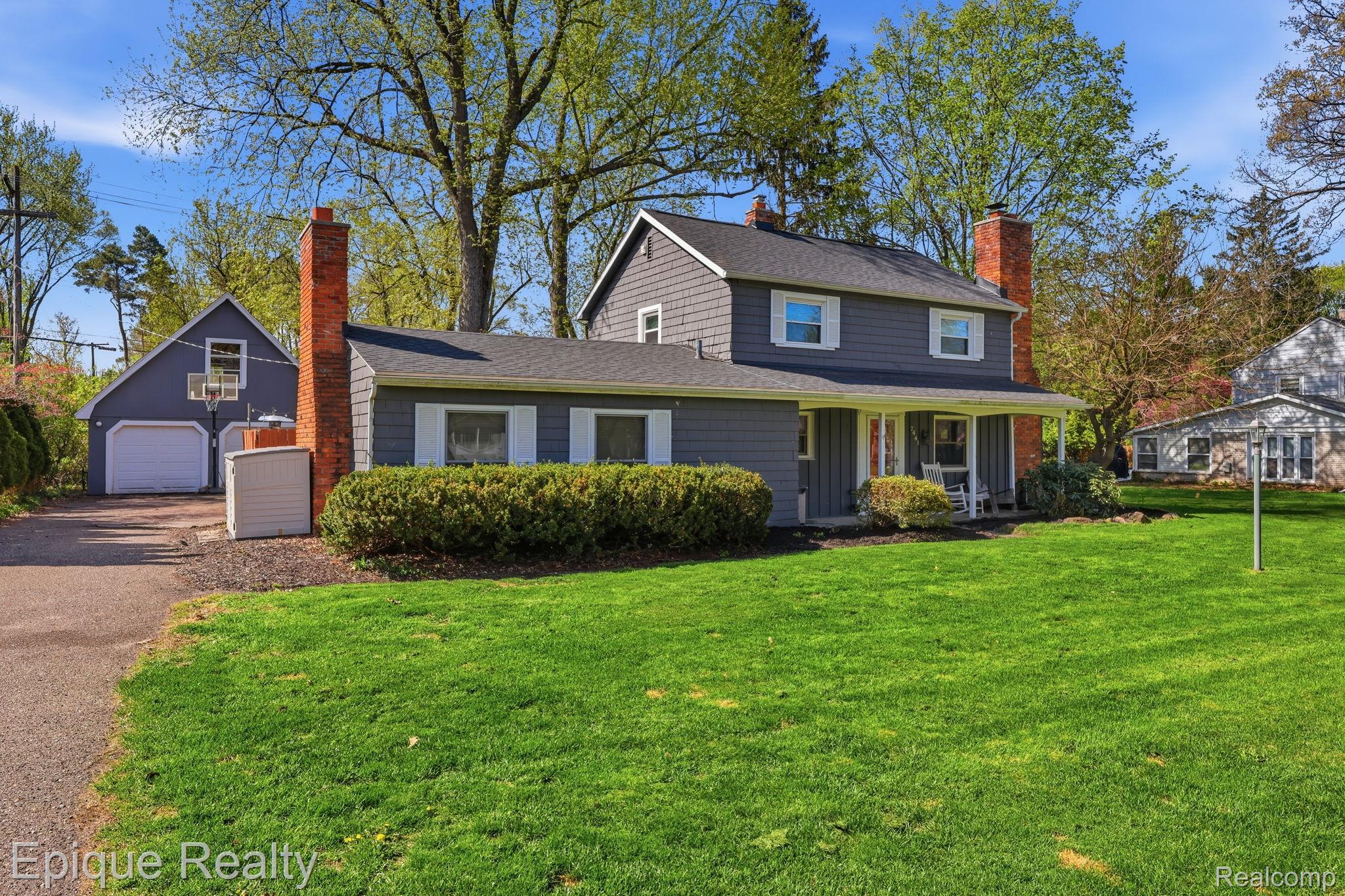 7441 Honeysuckle Road West Bloomfield, MI 48324 - Photo 1 of 35 View of front of house with covered porch, a front lawn, a chimney, a garage, and an outbuilding