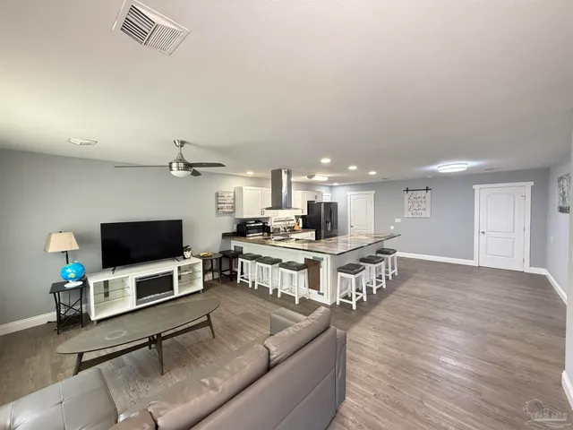 a living room with stainless steel appliances furniture and a flat screen tv