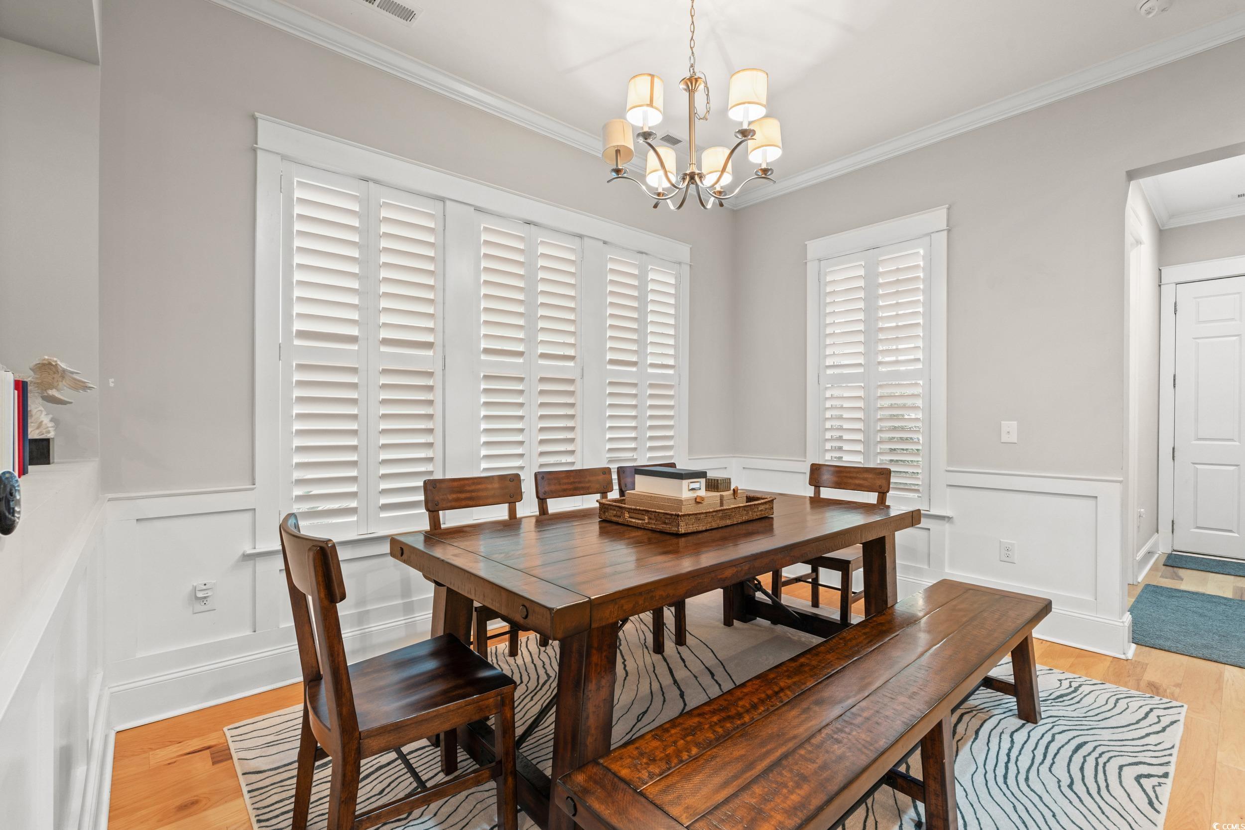 7809 Monarch Drive Myrtle Beach, SC 29572 - Photo 5 of 33 Dining area featuring crown molding, light wood-type flooring, a wainscoted wall, a chandelier, and a decorative wall
