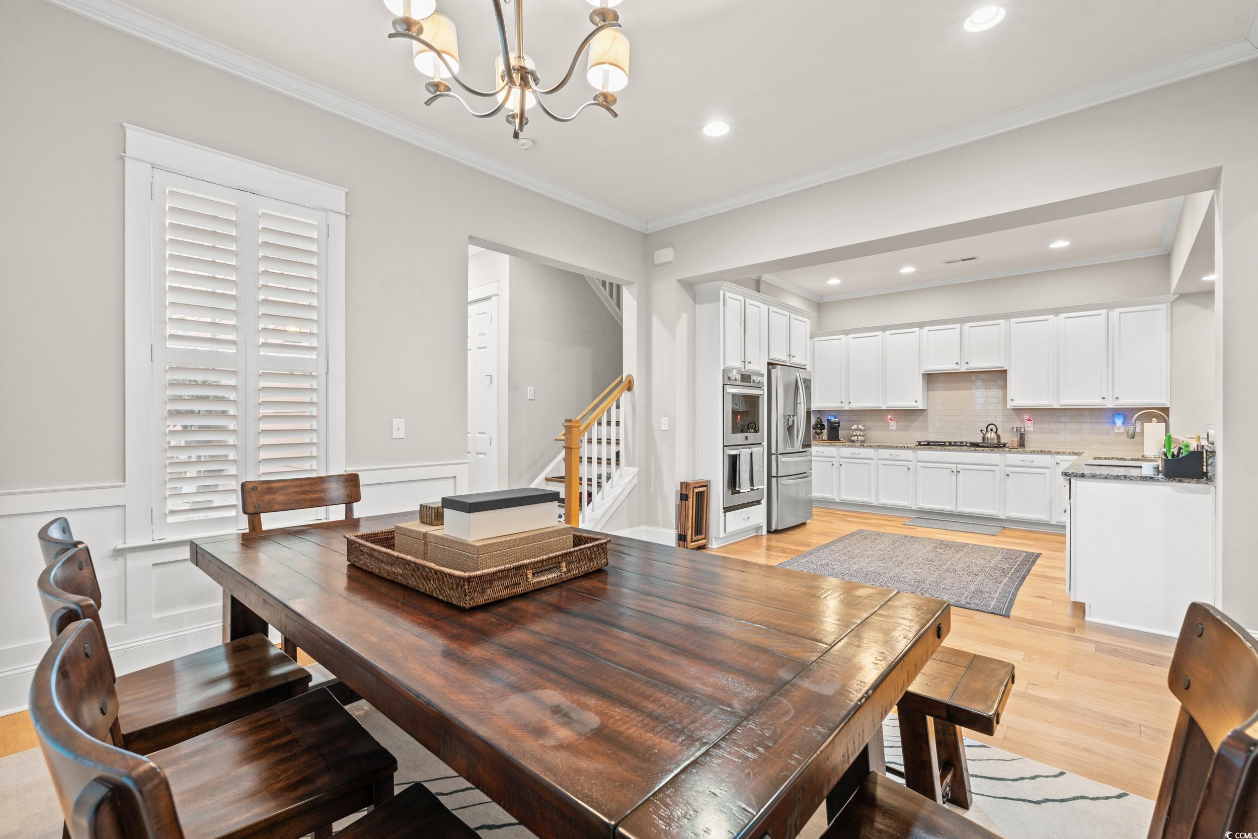7809 Monarch Drive Myrtle Beach, SC 29572 - Photo 6 of 33 Dining room with stairs, ornamental molding, a chandelier, light wood-type flooring, and a decorative wall