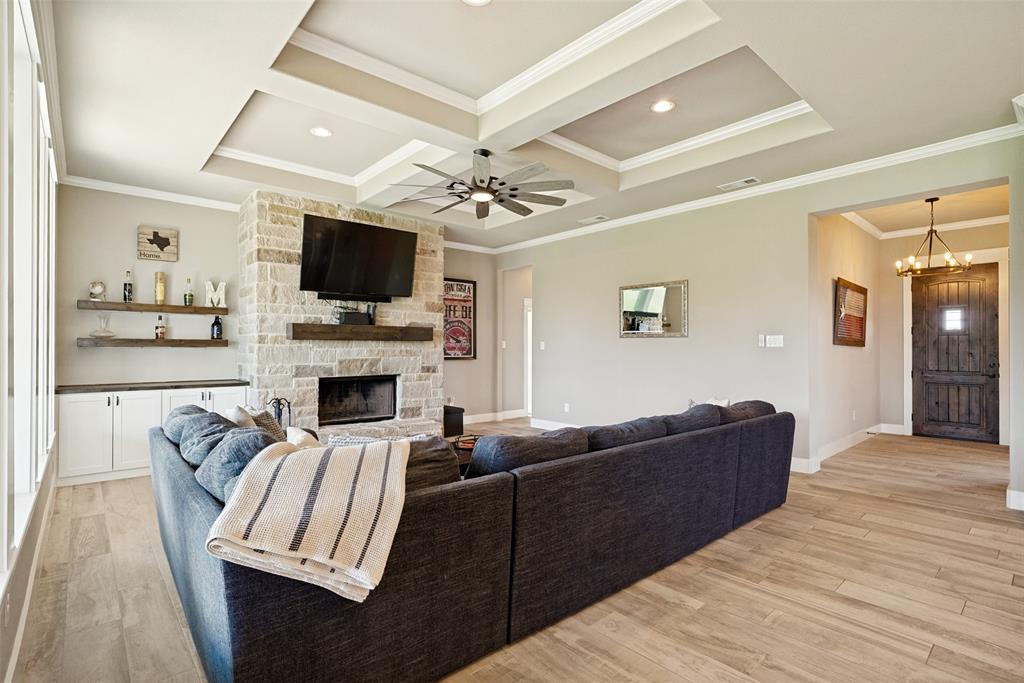 6913 Veal Station Road Weatherford, TX 76085 - Photo 3 of 31 Living area featuring a stone-clad fireplace with a wood mantel, recessed ceiling with a contemporary ceiling fan, and wood-finish flooring