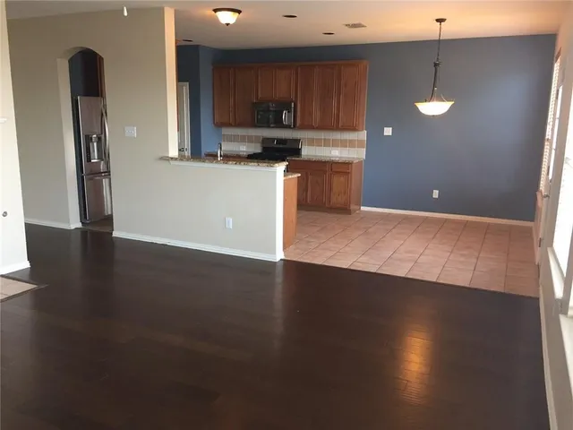 an open kitchen with kitchen island wooden floors and stainless steel appliances