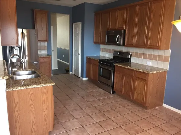 a kitchen with stainless steel appliances granite countertop a stove a refrigerator and a wooden cabinets