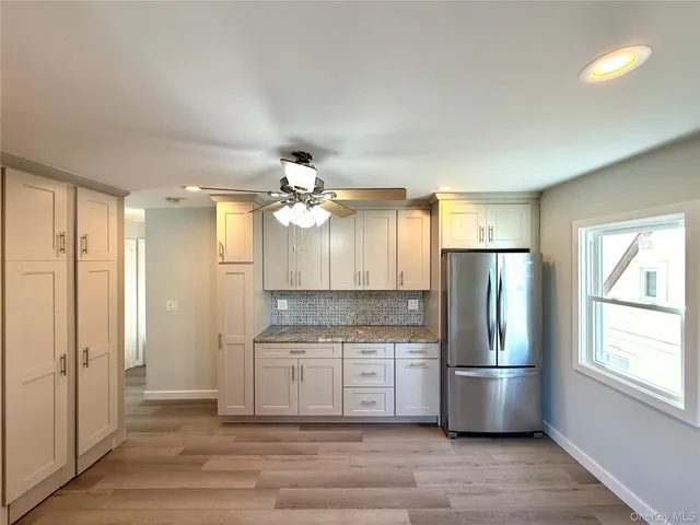 a view of a kitchen with a sink cabinet a refrigerator and windows