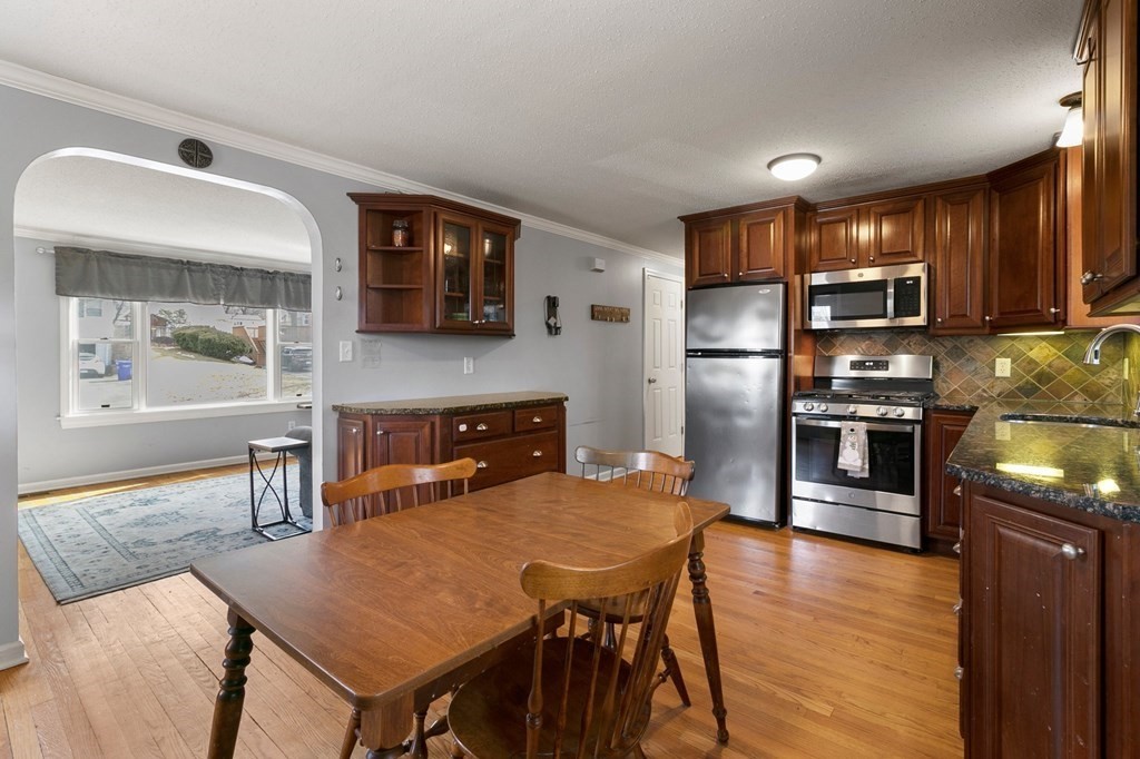 190 West Allen Ridge Road Springfield, MA 01118 - Photo 9 of 39 a kitchen with stainless steel appliances granite countertop a stove a refrigerator a sink a dining table and chairs with wooden floor