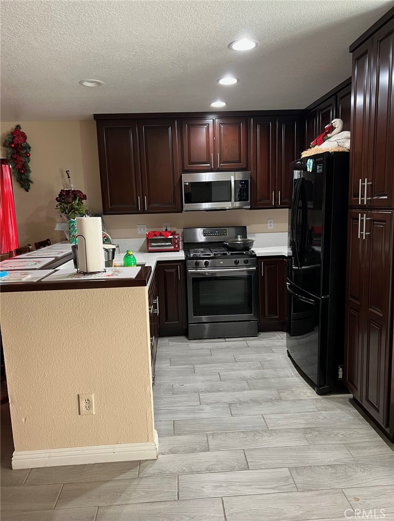 14565 Green River Road Victorville, CA 92394 - Photo 7 of 20 a kitchen with stainless steel appliances granite countertop a refrigerator stove a sink dishwasher and wooden cabinets