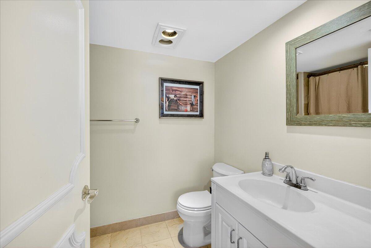 1 Harbourside Drive, Unit 3505 Delray Beach, FL 33483 - Photo 18 of 38 a bathroom with a toilet sink vanity and mirror