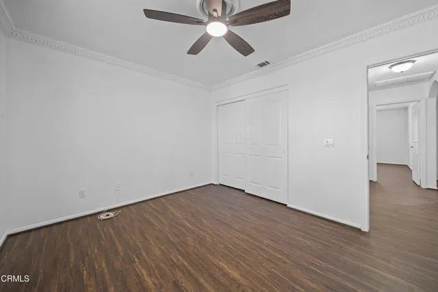 an empty room with wooden floor chandelier fan and closet area