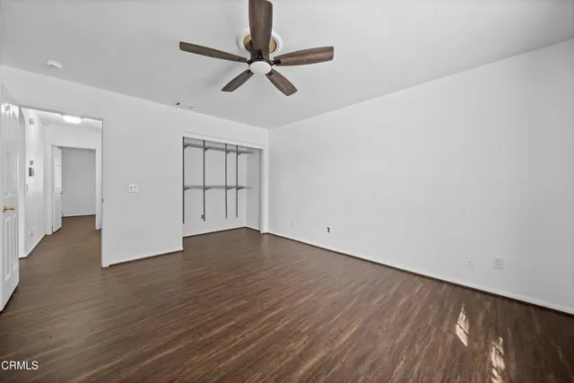an empty room with wooden floor fan and windows
