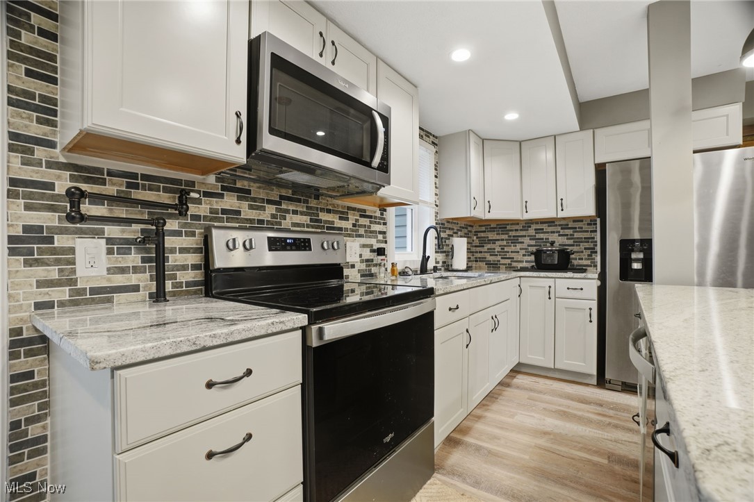 2146 Clay Road Dorset, OH 44032 - Photo 12 of 40 Kitchen with stainless steel appliances, light stone counters, white cabinetry, and recessed lighting
