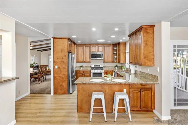 a kitchen with kitchen island granite countertop wooden cabinets and refrigerator