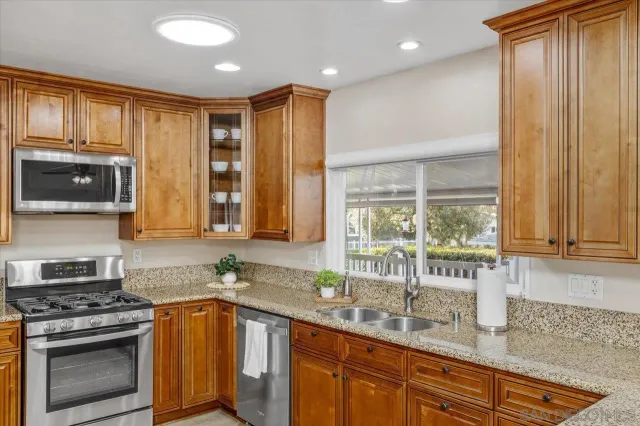 a kitchen with stainless steel appliances granite countertop a stove a sink and a microwave