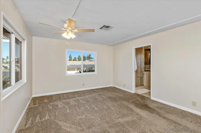 an empty room with windows and fan