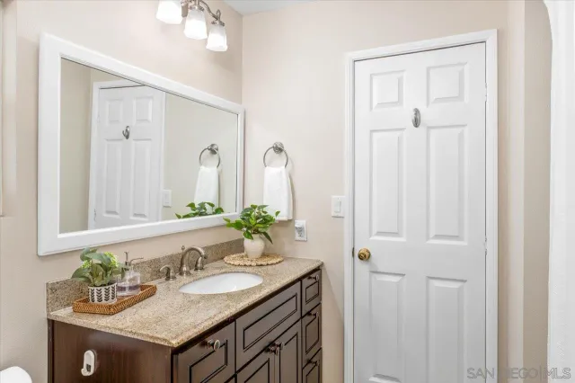 a bathroom with a granite countertop sink and a mirror