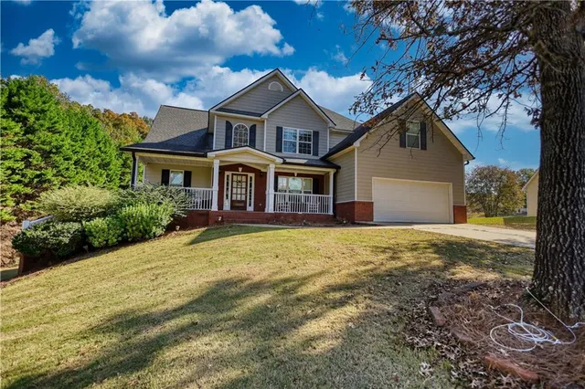 a view of a house with a yard and a large tree