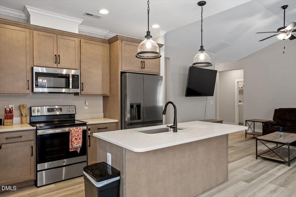 2810 Antioch Church Road Timberlake, NC 27583 - Photo 18 of 34 a kitchen with stainless steel appliances a stove a sink island and a refrigerator with wooden floor
