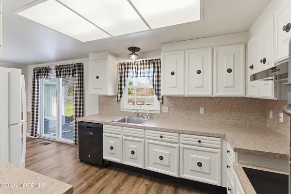 a kitchen with granite countertop a sink cabinets and wooden floor