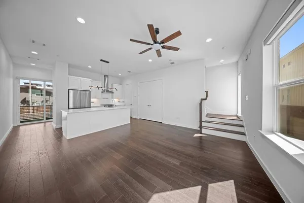 an empty room with wooden floor ceiling fan and windows