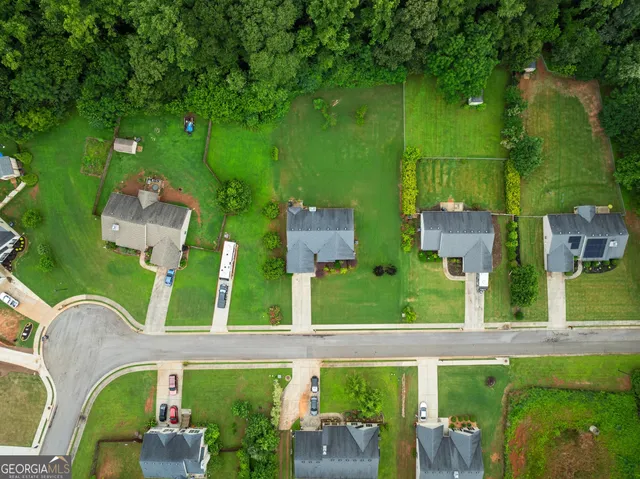an aerial view of residential houses with outdoor space and trees